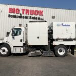Side view of a white sweeper truck