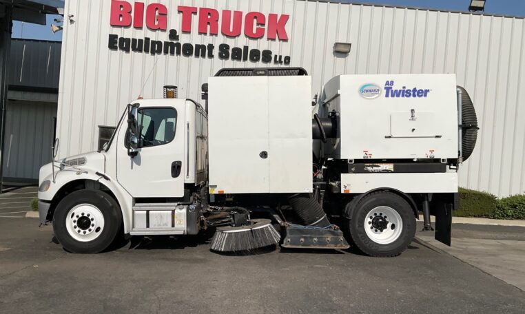 Side view of a white sweeper truck
