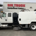 Side view of a white sweeper truck